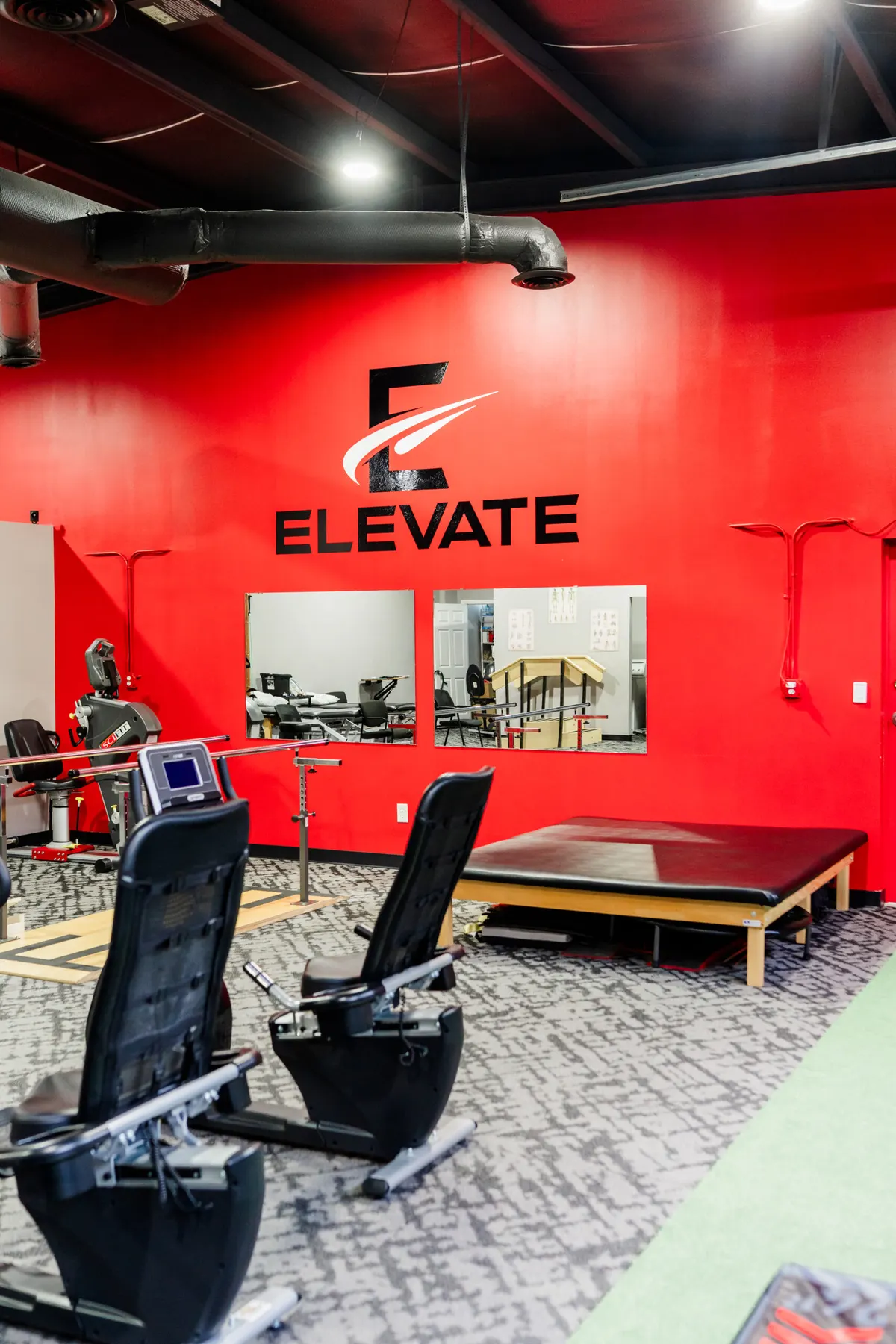 Elevate Physical Therapy gym with the red Elevate logo wall