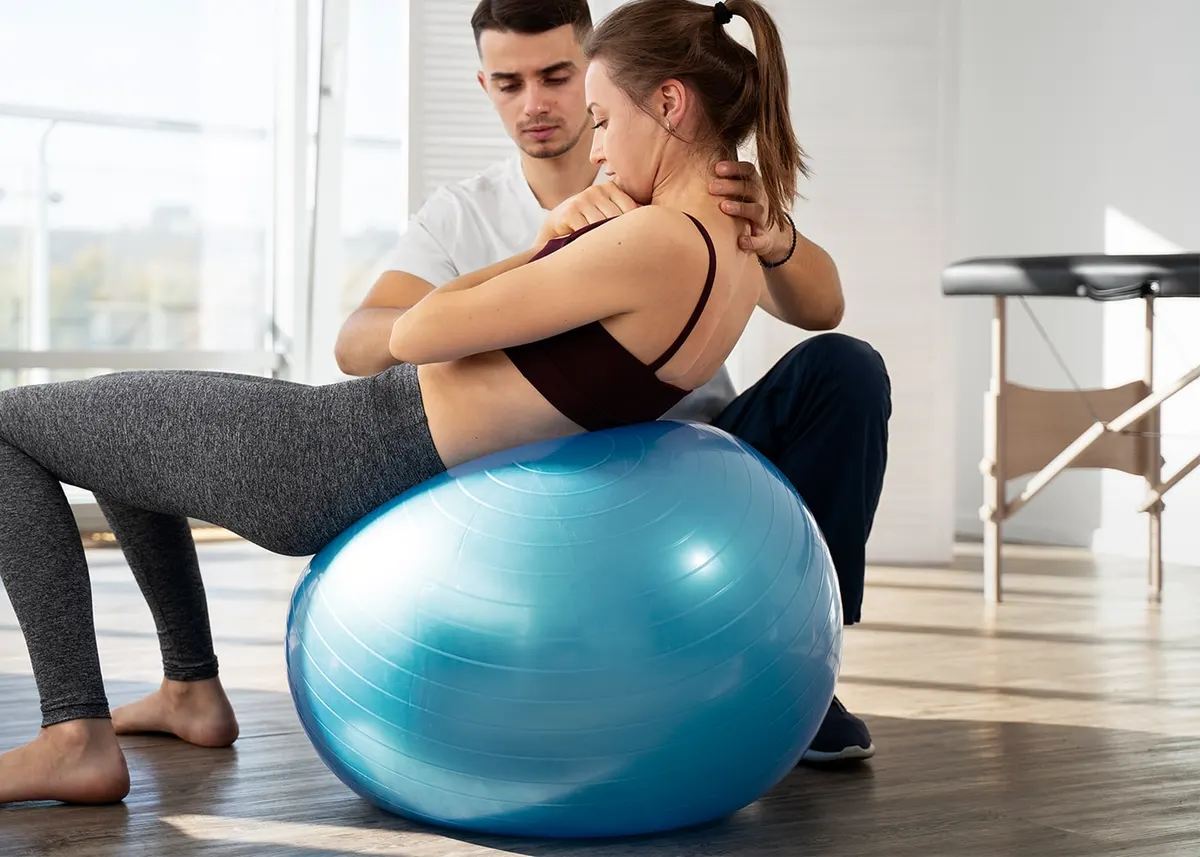 Patient doing a therapeutic exercise on a stability ball with a therapist